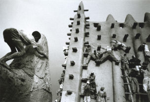 Metselaars smeren de nieuwe pleisterlaag uit over de hogere delen van het gebouw, Moskee van Djenné, Mali, 2000